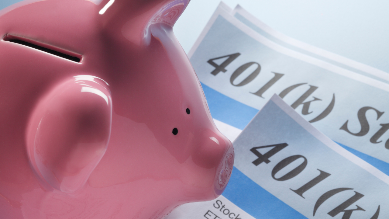 401k and IRA limits documents and pink piggy bank