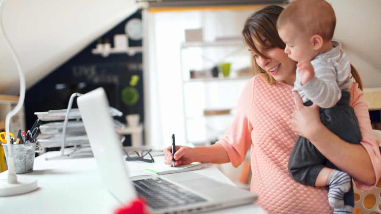 EITC Mom holding baby while working on computer