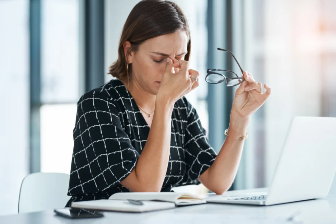 Woman exhausted at work rubbing her eyes