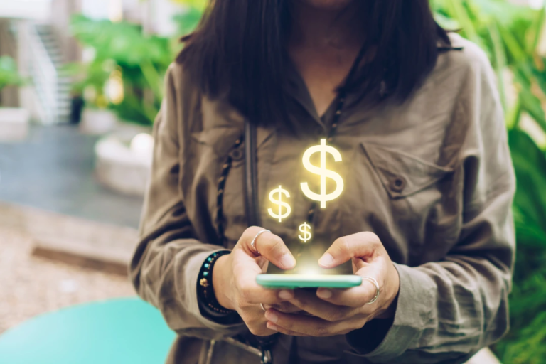 Money signs coming from mobile phone in woman's hand portraying direct deposit
