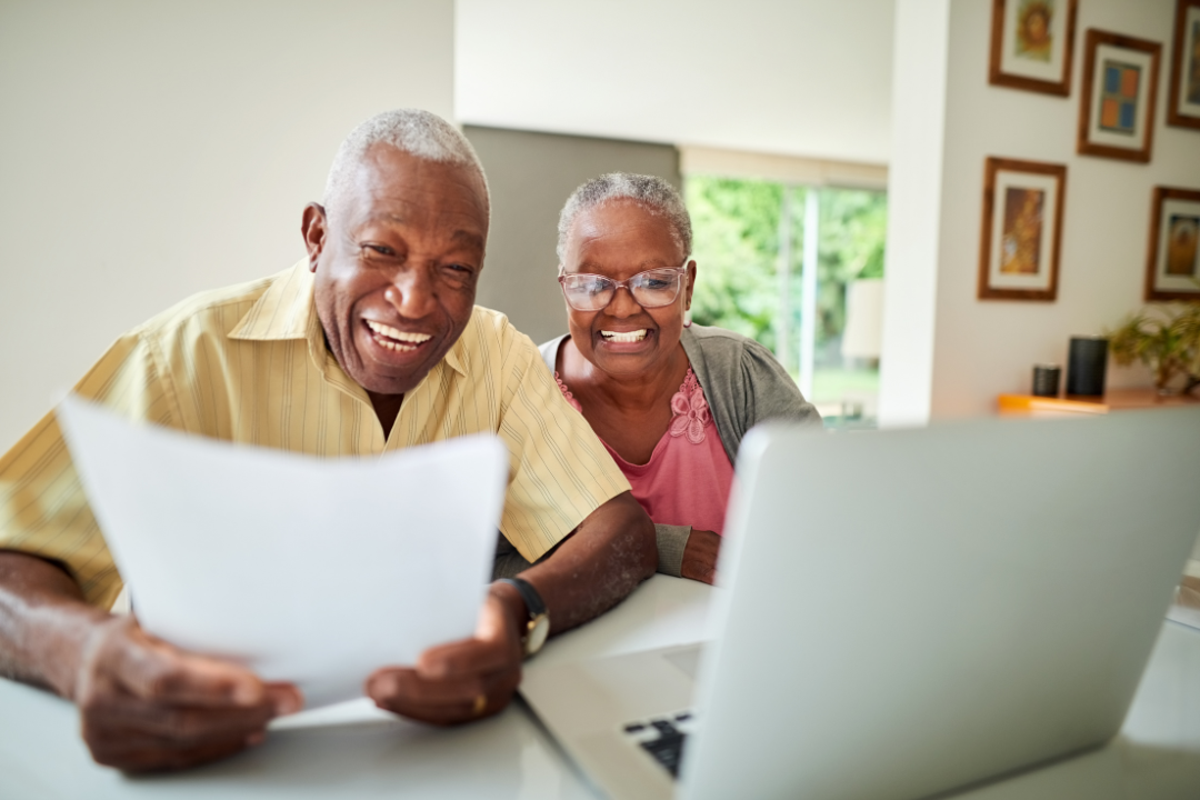 African American couple smiling looking at laptop as the plan retirement