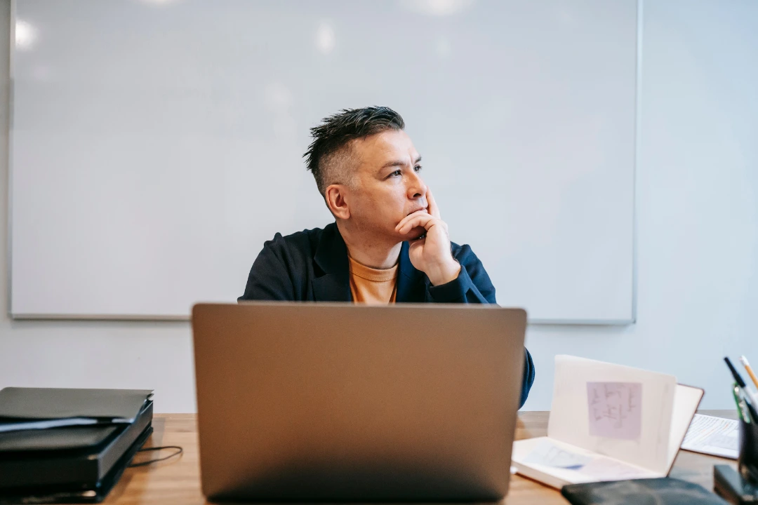 A thoughtful professional sitting at a desk, reflecting on what makes a good leader in today’s workplace.