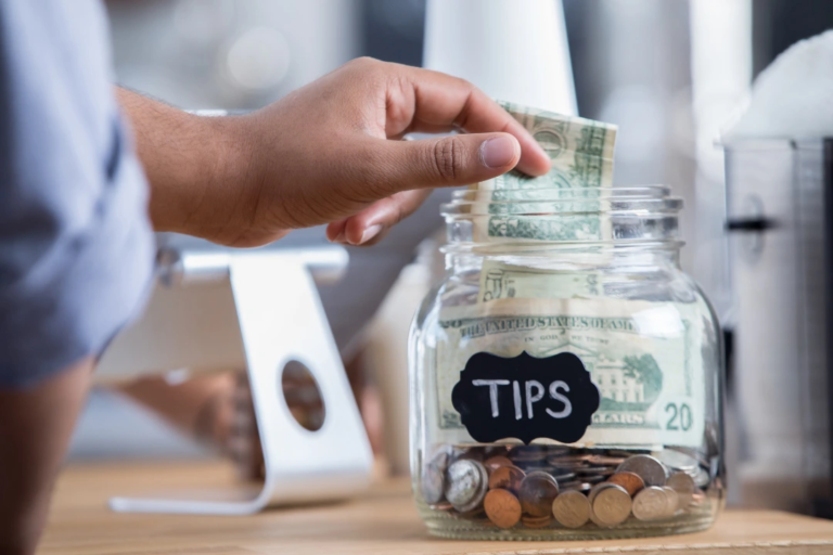 Close-up of a tip jar at a service counter, symbolizing income potentially impacted by the No Tax on Tips Act.