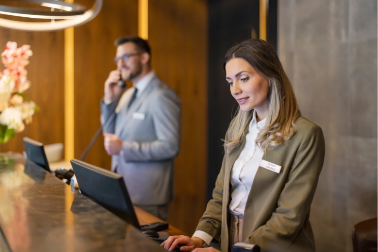 Hotel front desk staff reviewing employee data on screen—illustrating the importance of tracking hotel HR metrics like turnover, time-to-fill, and training rates.